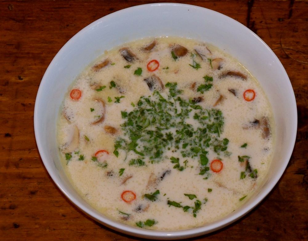 white soup with mushroom and green leaves on top - best thai food in thailand