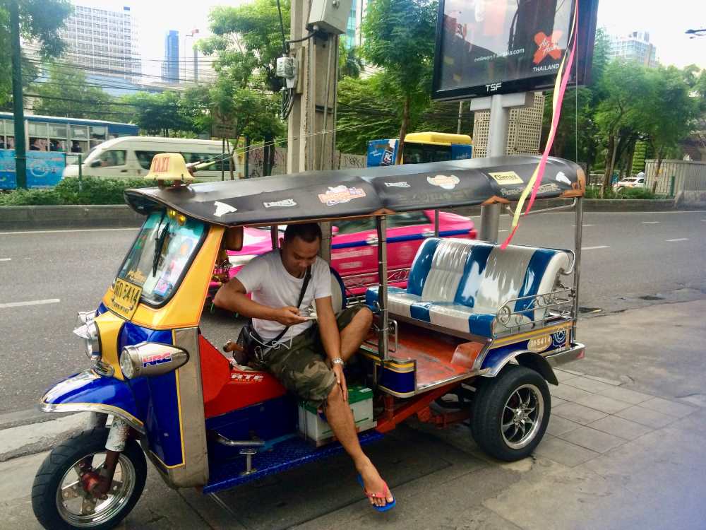 man sitting in a tuktuk ride beside the road
