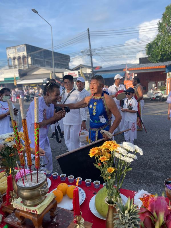 group of people in the road with fruits, flowers and candles in the red table a
