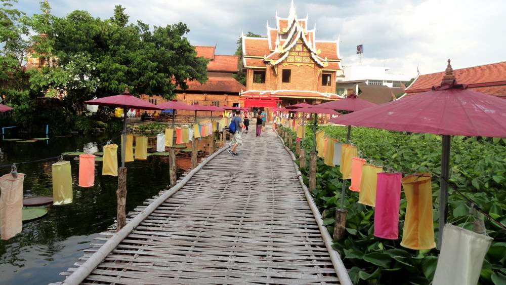 wooden pathway surrounded by body of water and plants going to the temple- chiang mai temples