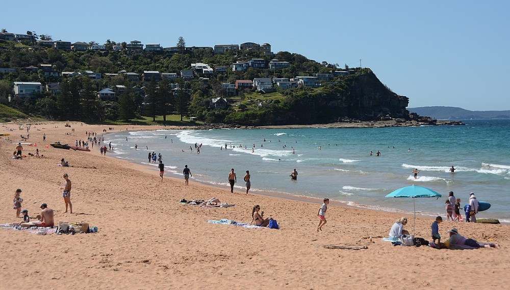 people walking, sitting at the sand and swimming at the beach