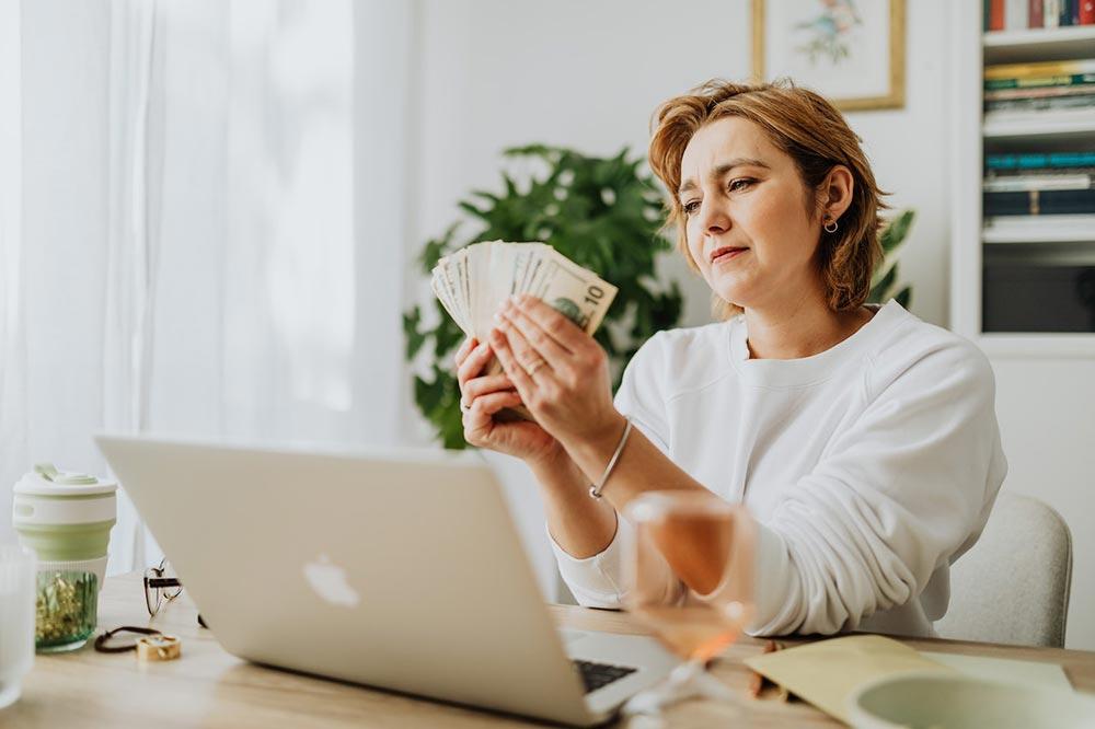 Image of a woman in front of her Mcbook counting moneys