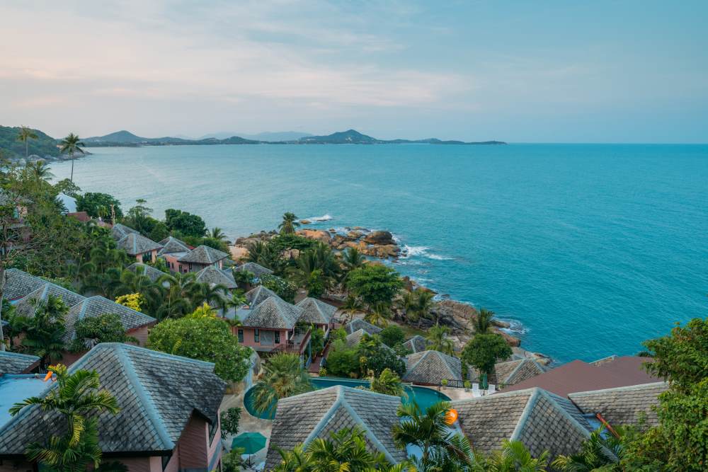 brown roofs of houses surrounded by green trees beside body of water