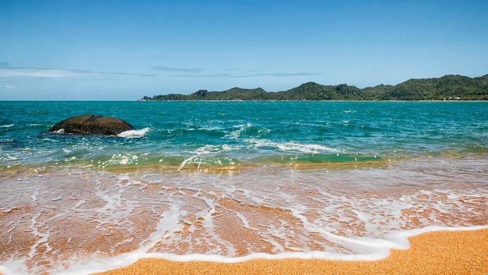 stunning green ocean near the orange color sand - Best Places To Visit In Queensland