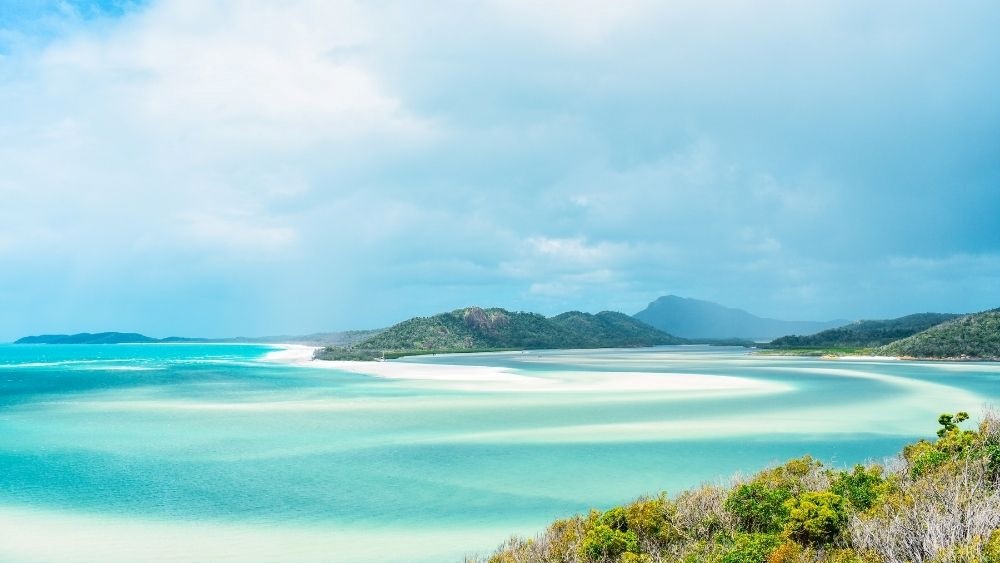 stunning blue beach surrounded by lushy green mountains