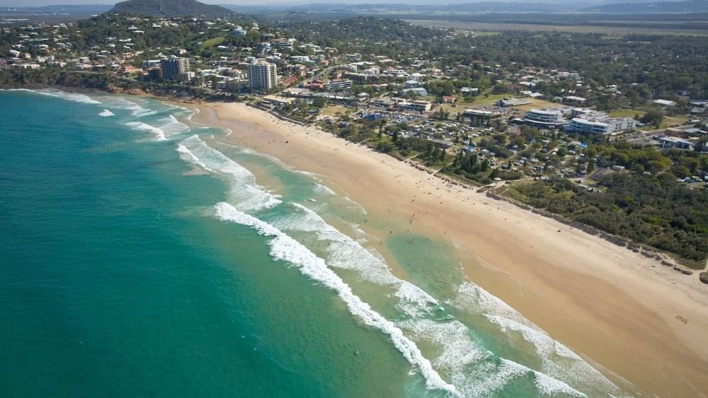 aerial view of green ocean in side is a community with building and houses
