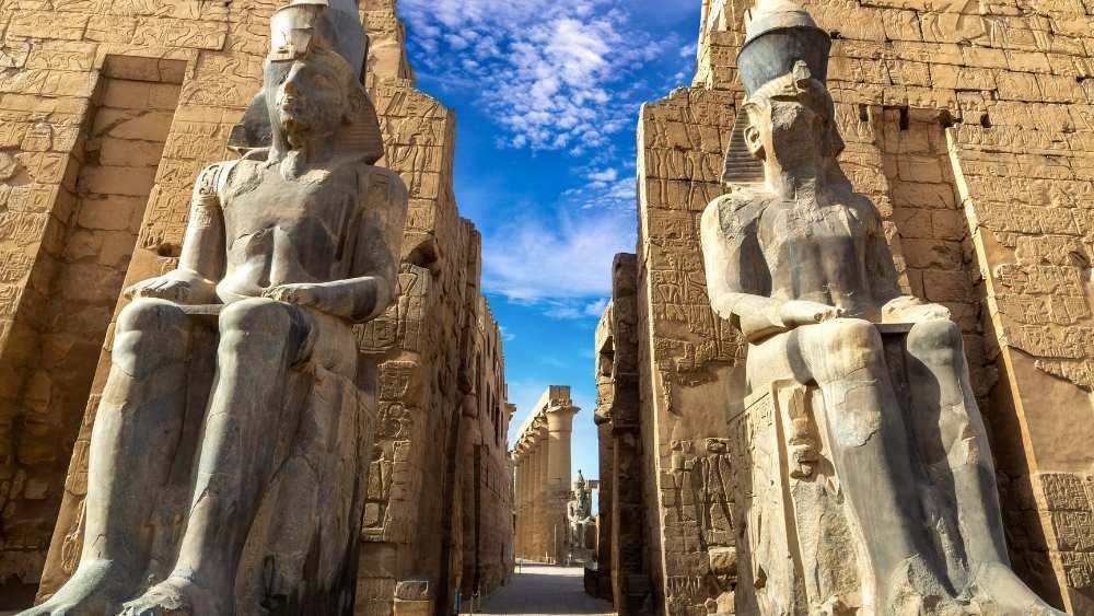 two huge statue of a pharaoh who is sitting at a throne