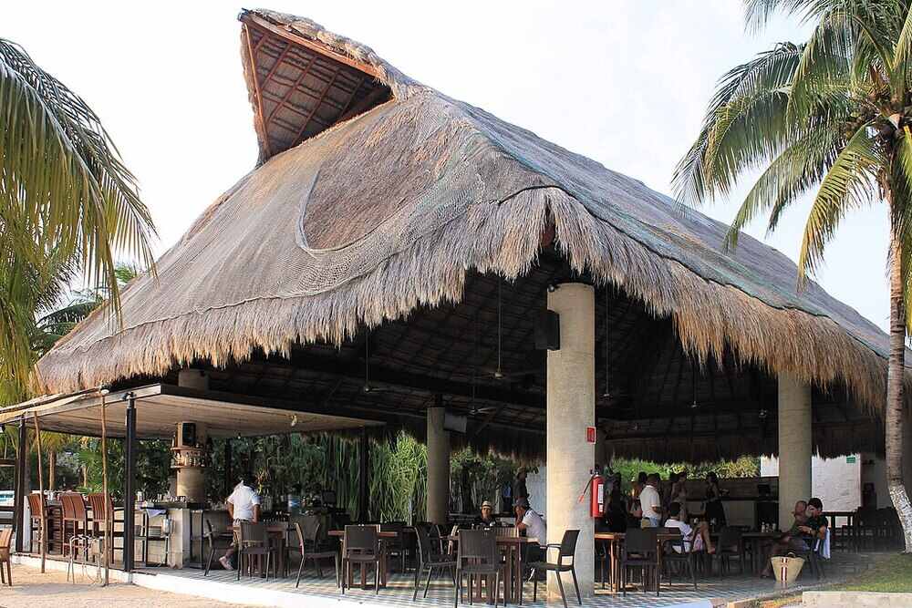 Opened big nipa hut lounge with bunch of people sitting and chatting