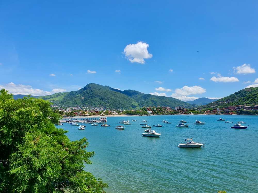 different kind of boat and yacht in the ocean surrounded by lushy green mountains- 25 Best Places to Visit in Mexico